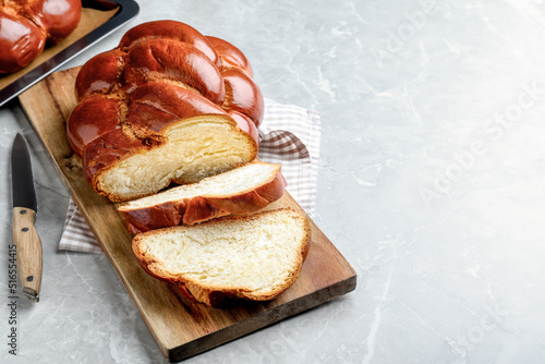 Cut homemade braided bread on grey table, space for text. Traditional Shabbat challah