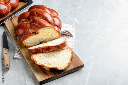 Cut homemade braided bread on grey table, space for text. Traditional Shabbat challah photo