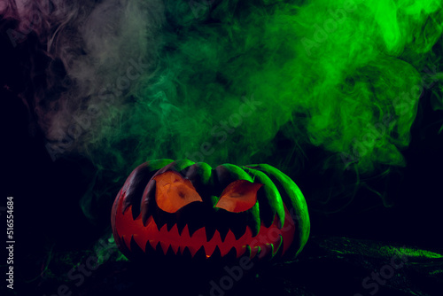 Composition of halloween carved pumpkin with smoke and green light on black background