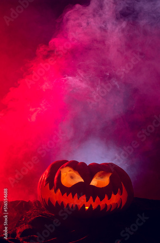 Composition of halloween carved pumpkin with smoke and red light on black background