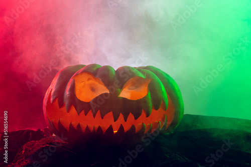 Composition of halloween carved pumpkin with smoke, green and red light on black background