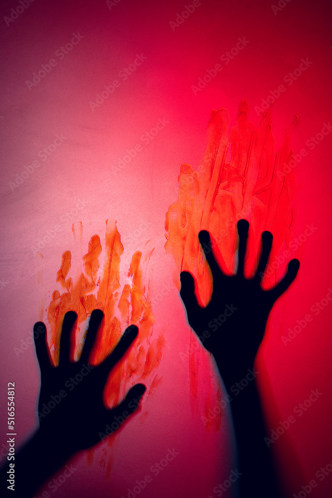 Composition of shape of black hands with blood stains on red background