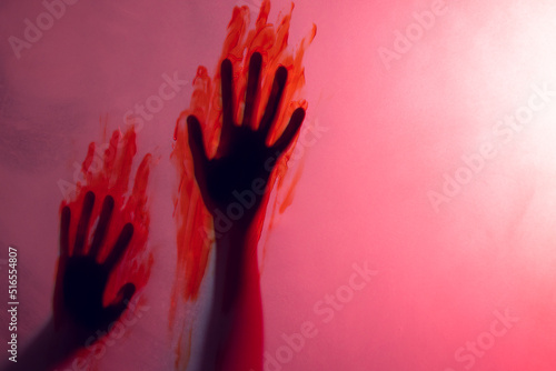 Composition of shape of hands with blood stains on red background