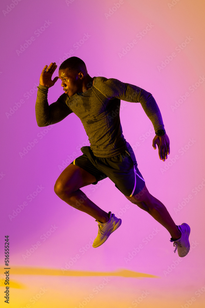 African american male runner with sportswear over pink lighting