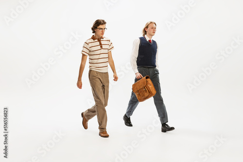 Portrait of two seriously looking man in retro style outfit walking isolated over white studio background