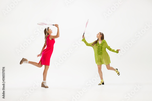 Portrait of two stylish young women playing tennis  posing isolated over white studio background