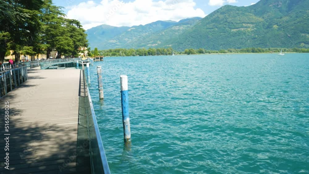The beautiful promenade of Lovere, Lake Iseo, Italy, a town of tourism and leisure. Turquoise rippled waters on the right. Italian alps and blue sky on the background. With copy-space. The beautiful promenade of Lovere, Lake Iseo, Italy, a town of tourism and leisure. Turquoise rippled waters on the right. Italian alps and blue sky on the background. With copy-space.