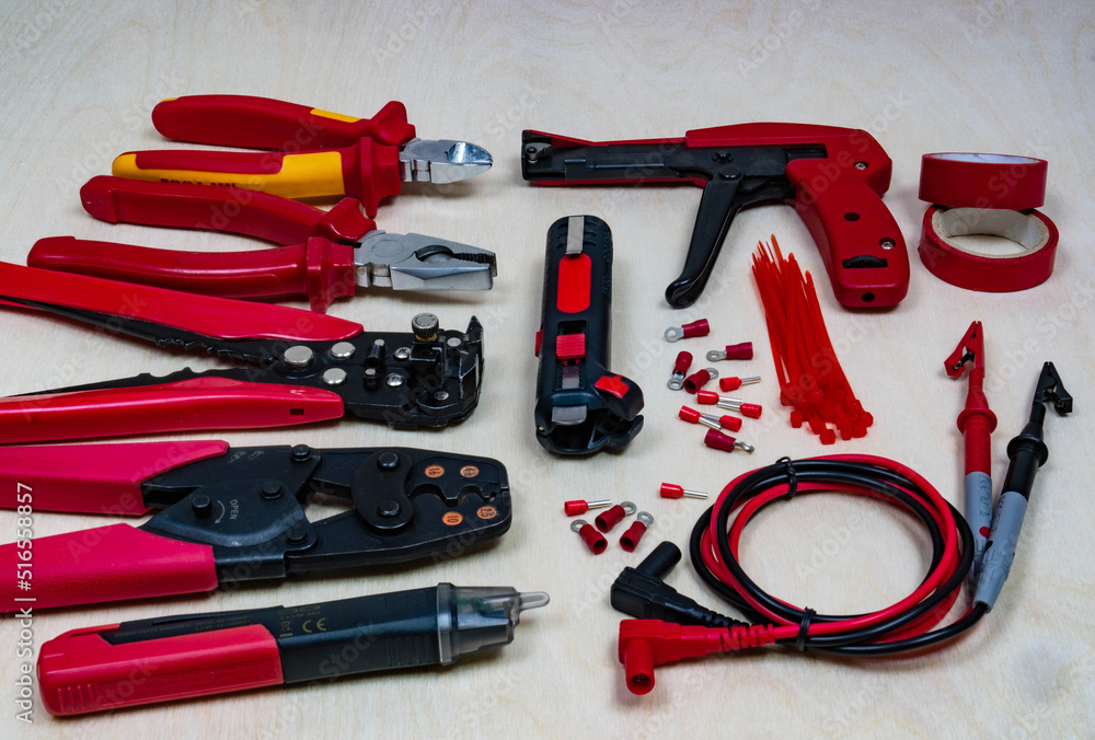 Red professional electrician tools on light wood background. Red professional electrician tools on light wood background.