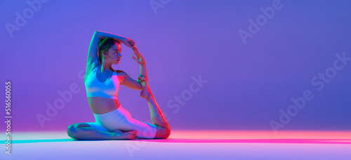 Fototapeta Naklejka Na Ścianę i Meble -  Studio shot of young flexible girl in fitness sport uniform practicing isolated on gradient pink-purple background in neon light. Sport, beauty, ad