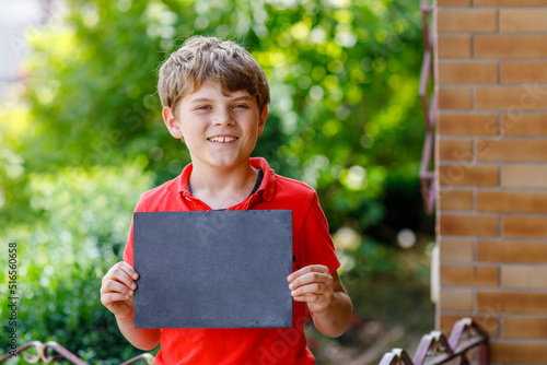 Happy little kid boy with backpack or satchel and glasses. Schoolkid on the way to school. Healthy adorable child outdoors On desk Last day third grade in German. School's out photo