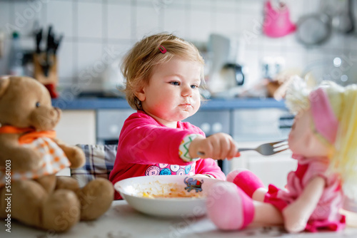 Fotografie, Obraz Adorable baby girl eating from fork vegetables and pasta