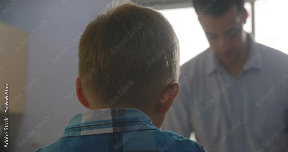 Close up shot of a back of a young boy and his father in the background. Close up shot of a back of a young boy and his father in the background.
