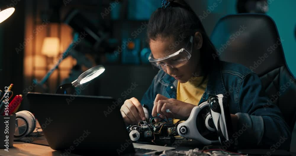 A busy girl sits at her desk in a dark room lit by an office lamp, a ...