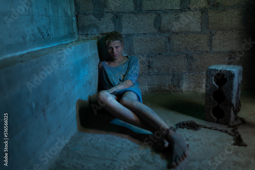Fotografie A young dirty man in tattered clothes is locked in a concrete basement