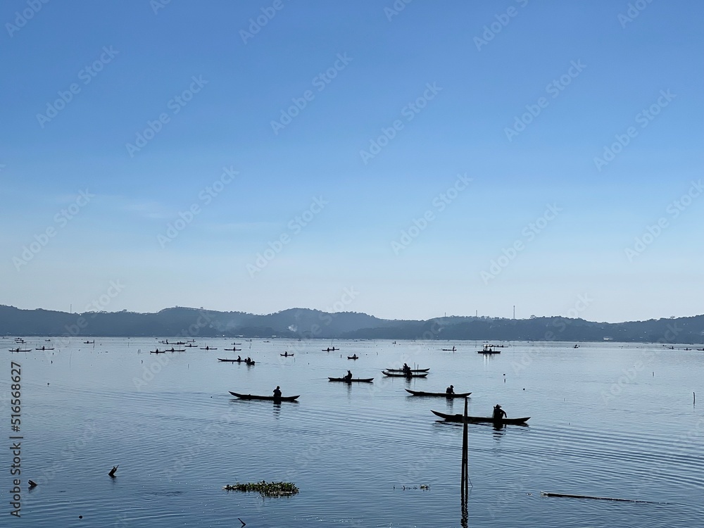 Beautiful Calm Water Reflection Lake and Fisherman working fishing on Boats with Blue Sky and Sunny Weather Clear Horizon
