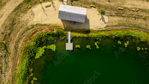 фотографія wooden pier on lake with small house next to with water lilies nymphea