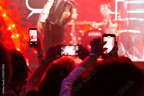 Spectators near the stage shoot their favorite artist on a smartphone. Silhouette of a concert crowd.