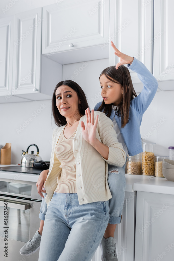 girl sitting on worktop in kitchen and scaring nanny. girl sitting on worktop in kitchen and scaring nanny.