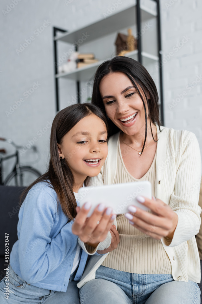 child and nanny smiling near blurred smartphone during video call at home. child and nanny smiling near blurred smartphone during video call at home.