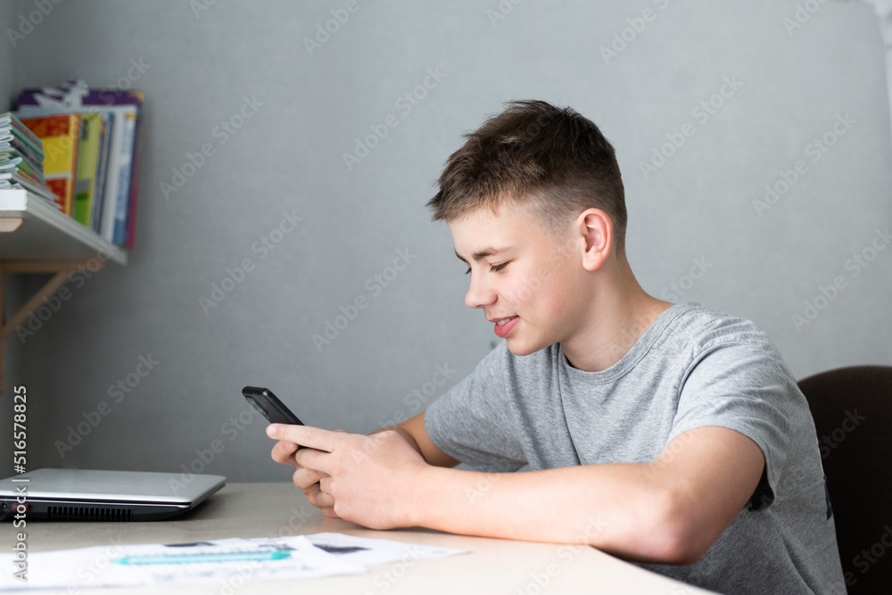 teenage boy using smartphone for study or communication, smiling and looking at screen teenage boy using smartphone for study or communication, smiling and looking at screen