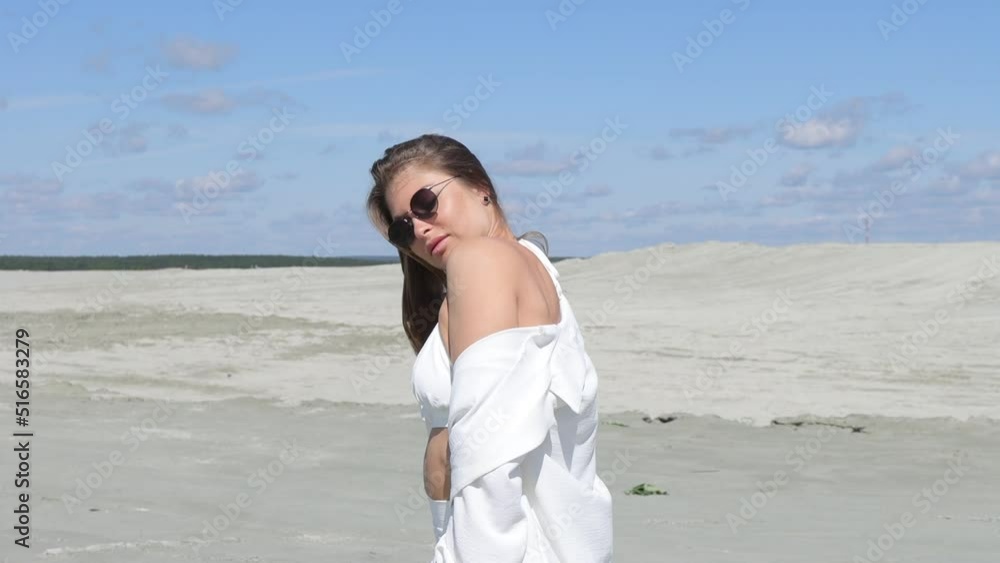 Charming woman standing on beach on windy day Charming woman standing on beach on windy day