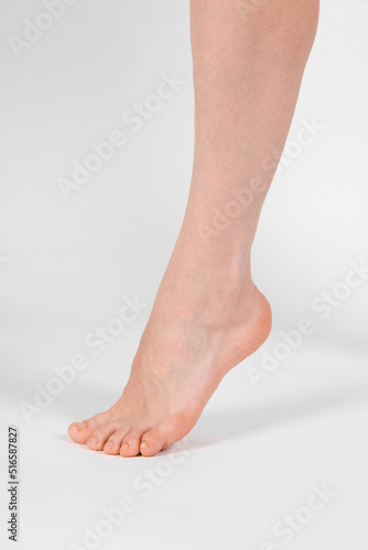 Fototapeta Naklejka Na Ścianę i Meble -  Barefoot and legs isolated on white background. Closeup shot of healthy beautiful female feet. Health and beauty concept. Side view of human foot ream with neutral manicure or pedicure. Sole of foot