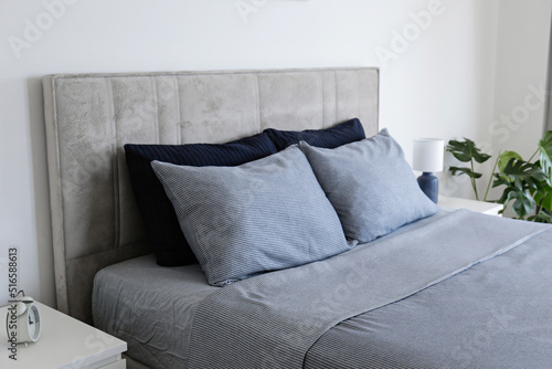 Fotografie Hotel room with freshly made king sized bed with headboard, perfectly clean and ironed sheets, puffy pillows in natural sun light