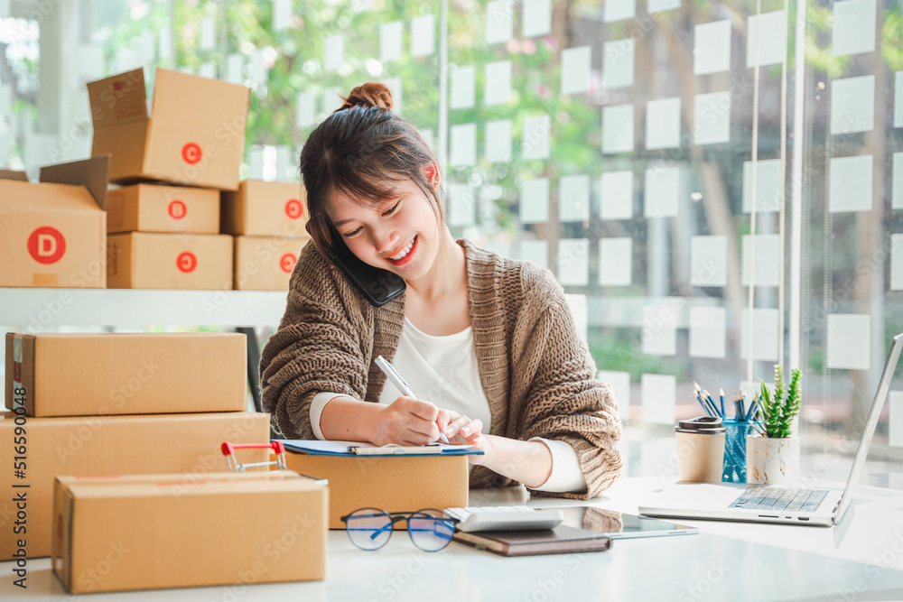 Portrait of a Small Business Startup, SME Owner, Female Entrepreneur work on parcel boxes Receipts and check orders online to prepare boxes. Selling to customers. Online SME business idea. Portrait of a Small Business Startup, SME Owner, Female Entrepreneur work on parcel boxes Receipts and check orders online to prepare boxes. Selling to customers. Online SME business idea.