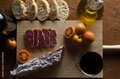 close up of a spanish food,tomato,wine,bread, sausage and olive oil on a wooden table photo