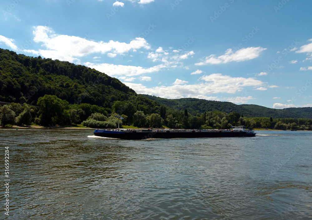 Frachtschiff auf dem Rhein bei Andernach in Rheinland-Pfalz vor blauem Himmel.