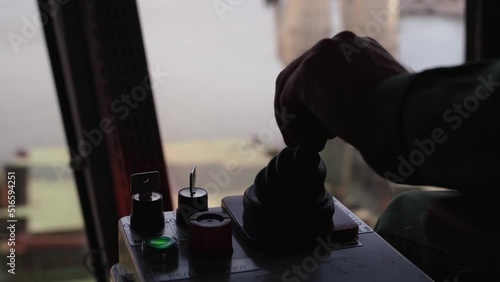 Man hands control joysticks at grain terminal operator cabin workplace. Worker controlling loading grain with arm lever handle from silo to bulker ship via moving trunk machine in dock.