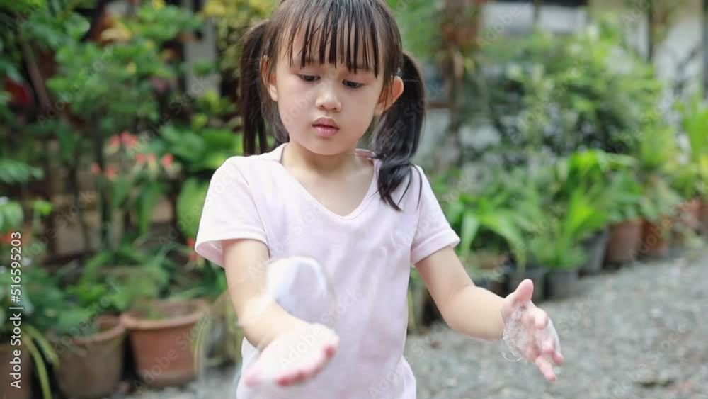 Little girl playing with soap foam and blowing it from hands. Concept for children play development and fun at home activity. Little girl playing with soap foam and blowing it from hands. Concept for children play development and fun at home activity.