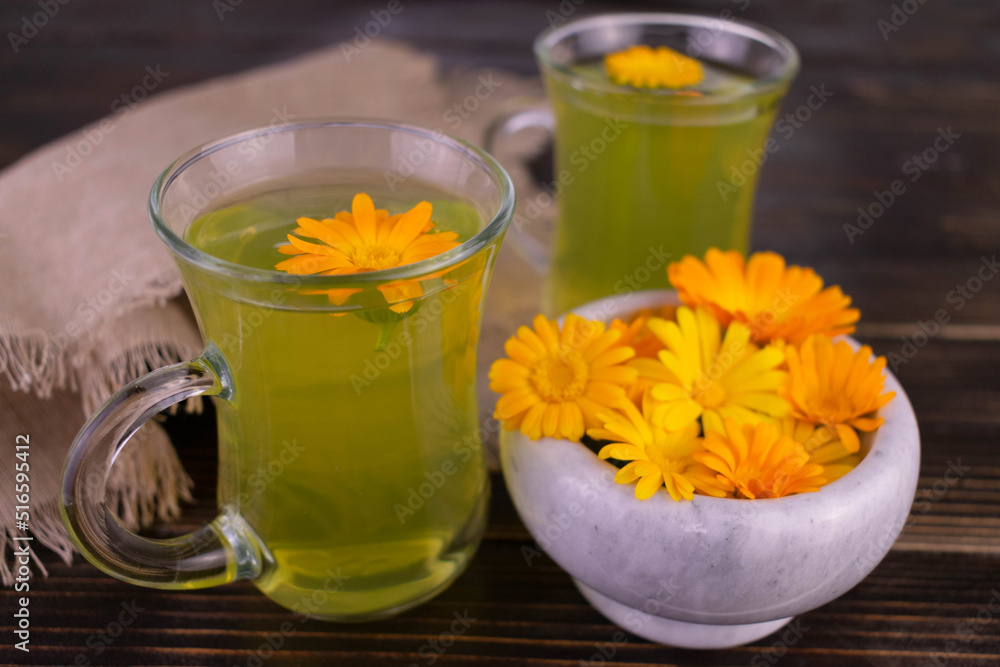 Marigold flower tea on a dark wooden background.
Marigold flower tea on a dark wooden background.