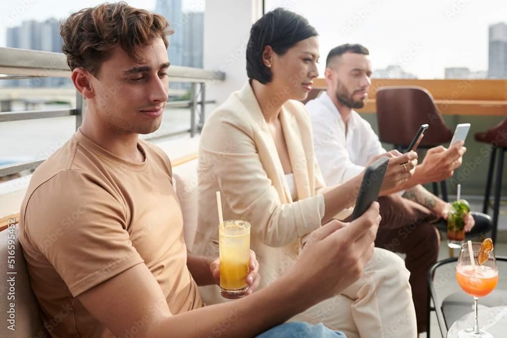Young people spending time on social media instead of socializing at rooftop party Young people spending time on social media instead of socializing at rooftop party