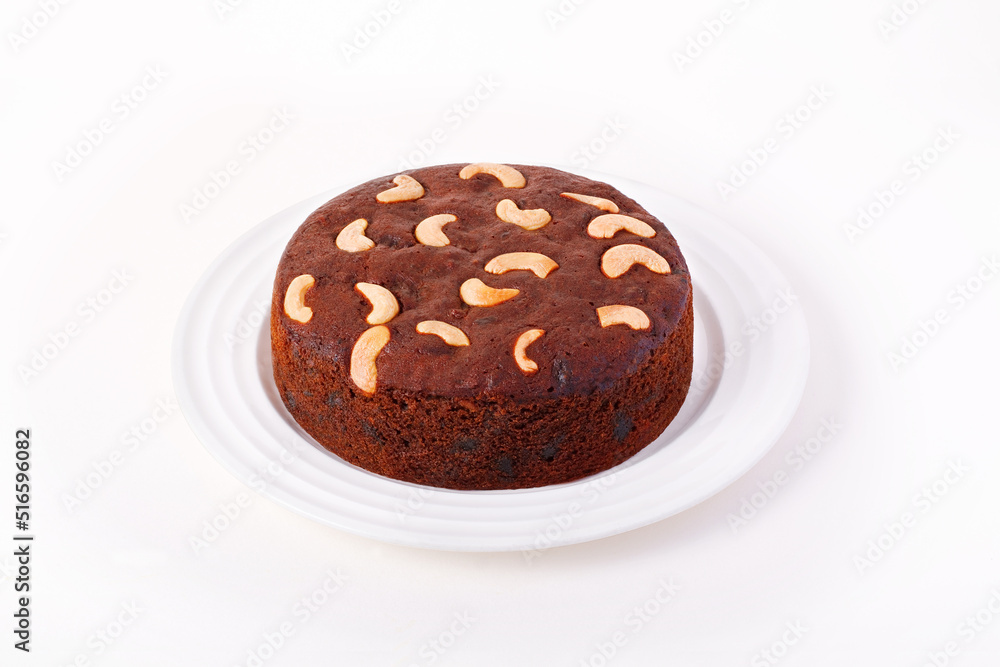 Plum cake with cashew nuts on a white plate Plum cake with cashew nuts on a white plate