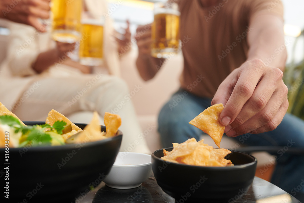 Close-up image of young people having corn chips while drinking beer in bar Close-up image of young people having corn chips while drinking beer in bar