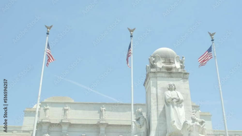 Three American flags waving in the wind to the backdrop of clear blue skies... in front of marble structures
