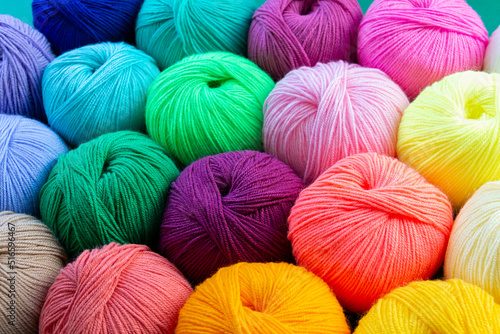 Colorful multicolored background from skeins of acrylic yarn. Textile industry. Arranged balls of yarn. Natural and neon colors.