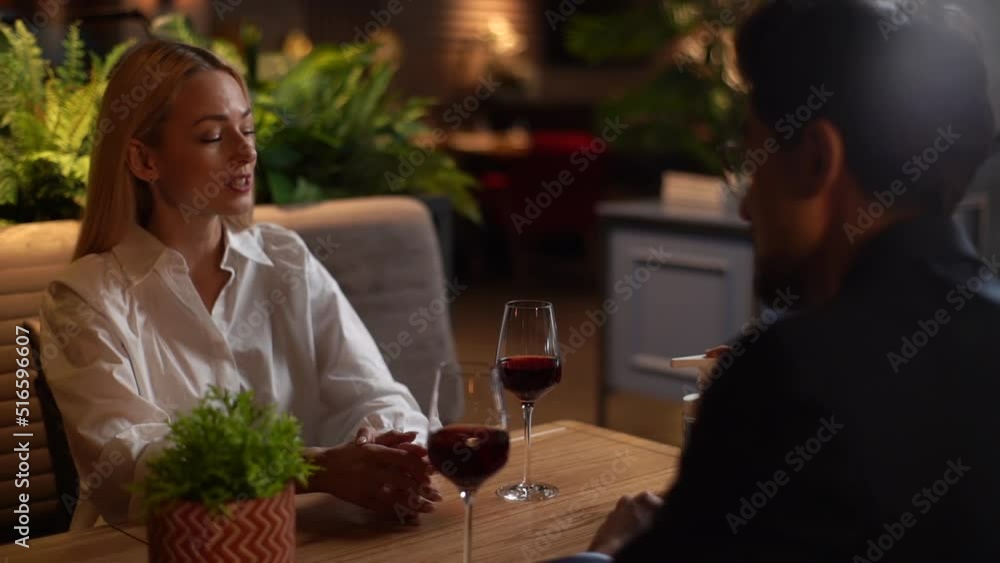 Happy young man and woman sitting at restaurant table using hand sanitizer before eating. Elegant male helping disinfect hands to blonde female during romantic dinner date. Shooting in slow motion. Happy young man and woman sitting at restaurant table using hand sanitizer before eating. Elegant male helping disinfect hands to blonde female during romantic dinner date. Shooting in slow motion.