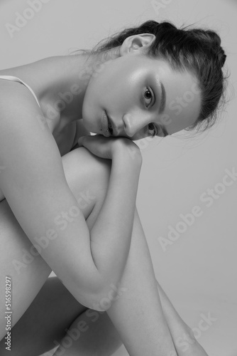 Portrait of tender young woman sitting  posing. Black and white photography aesthetics. Attentive look
