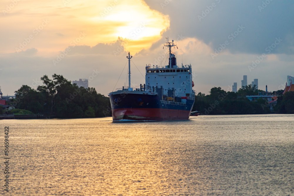 A large cargo ship in the middle of the Chao Phraya River, morning sunrise, Thailand.
