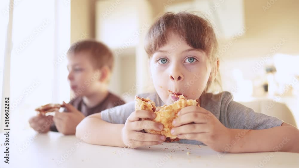 children eat burgers. fast food burger. a group of small children in the kitchen greedily eat fast food burgers. big family small kids having breakfast in the morning in the kitchen eating burger sun children eat burgers. fast food burger. a group of small children in the kitchen greedily eat fast food burgers. big family small kids having breakfast in the morning in the kitchen eating burger sun