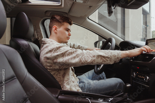 Young zoomer driver sets special settings on display of control panel in car. Electronic control of vehicle elements photo