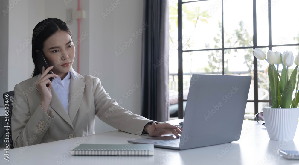 Asian businesswoman talking on a cell phone with a serious expression while working in the office
