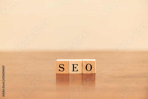 SEO。Search Engine Optimization。検索エンジン最適化。木製のブロックに描かれているSEOの文字。木製のテーブルの背景。