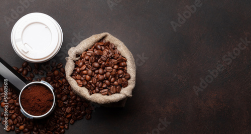Takeaway cup, roasted coffee beans and ground coffee in holder