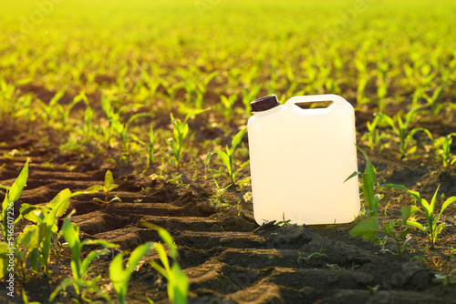 Blank white herbicide canister can in corn seedling field in springtime sunset photo
