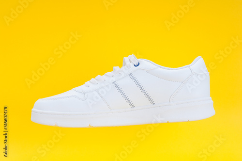 Single white sport sneaker close up on yellow background