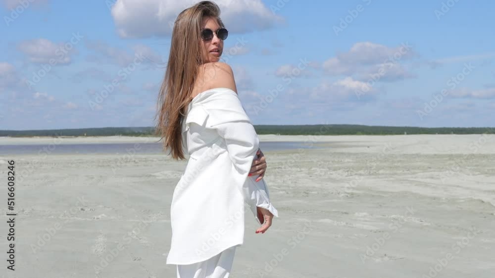 Charming woman standing on beach on windy day Charming woman standing on beach on windy day