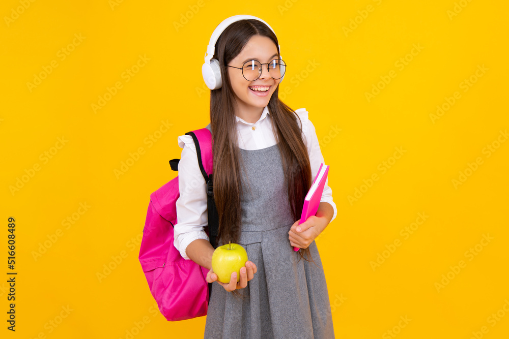 Back to school. School child, teenage student girl with bagpack hold apple and book isolated on yellow. Happy face, positive and smiling emotions of teenager girl. Back to school. School child, teenage student girl with bagpack hold apple and book isolated on yellow. Happy face, positive and smiling emotions of teenager girl.